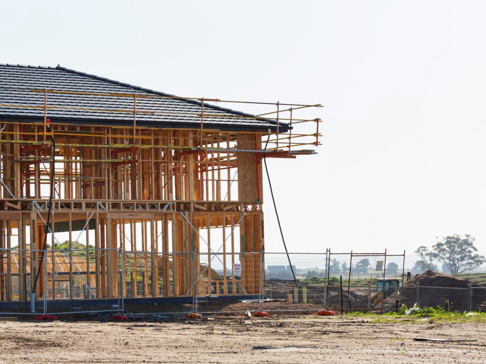 Timber-framed house under construction on a residential lot