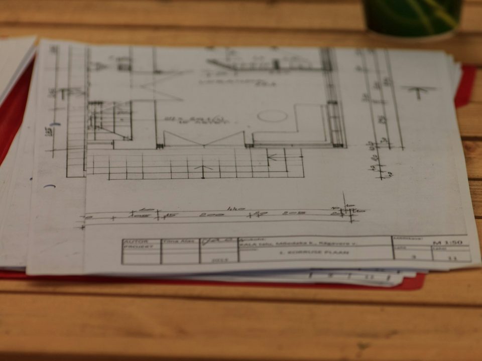 Printed floor plans and project drawings spread on a wooden table